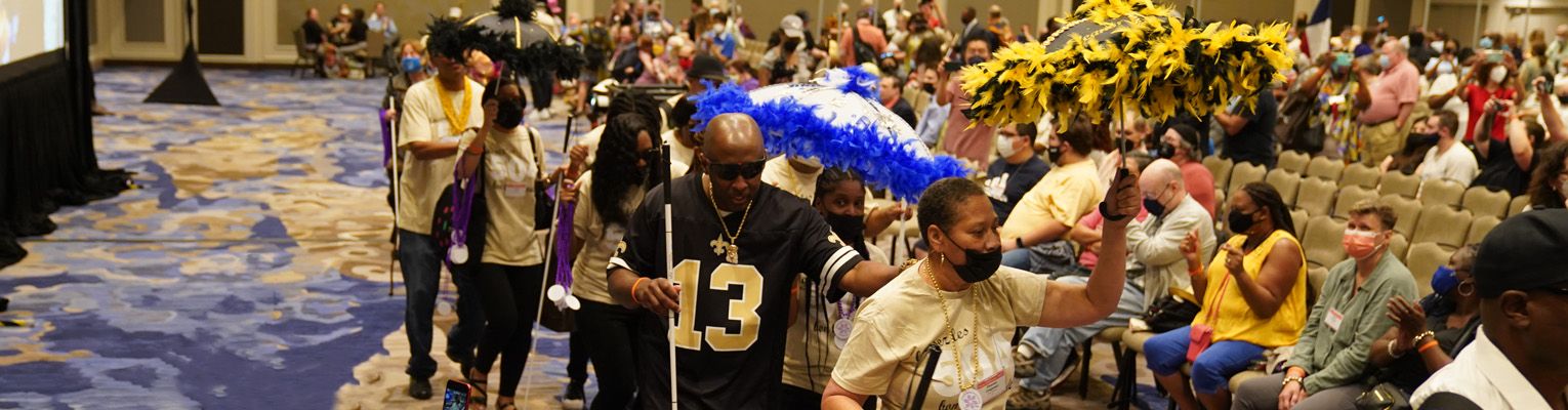 Photo of a New Orleans themed parade of five NFB members at the opening ceremonies of the 2022 National Convention.