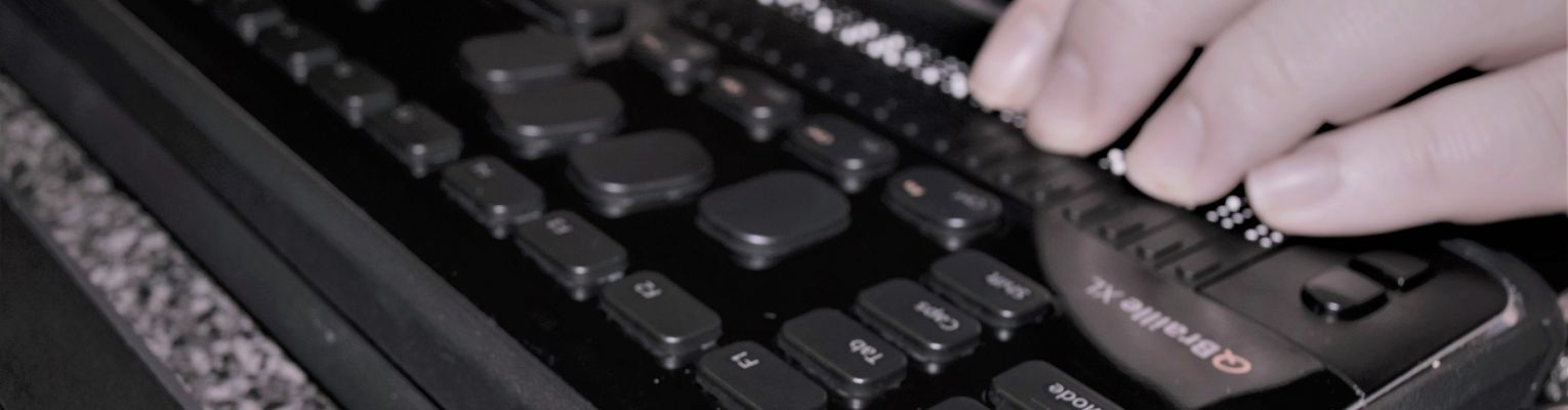 A person's hands rest on a HIMS QBraille XL device.