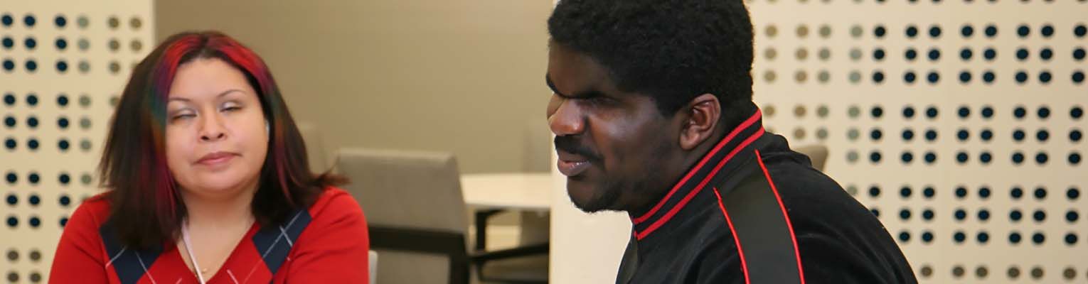 At a table, Danielle listens thoughtfully to a blind man sharing his story.