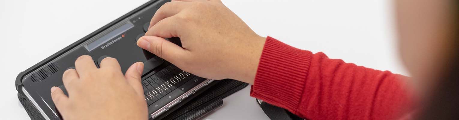 A close up of hands using a BrailleSense